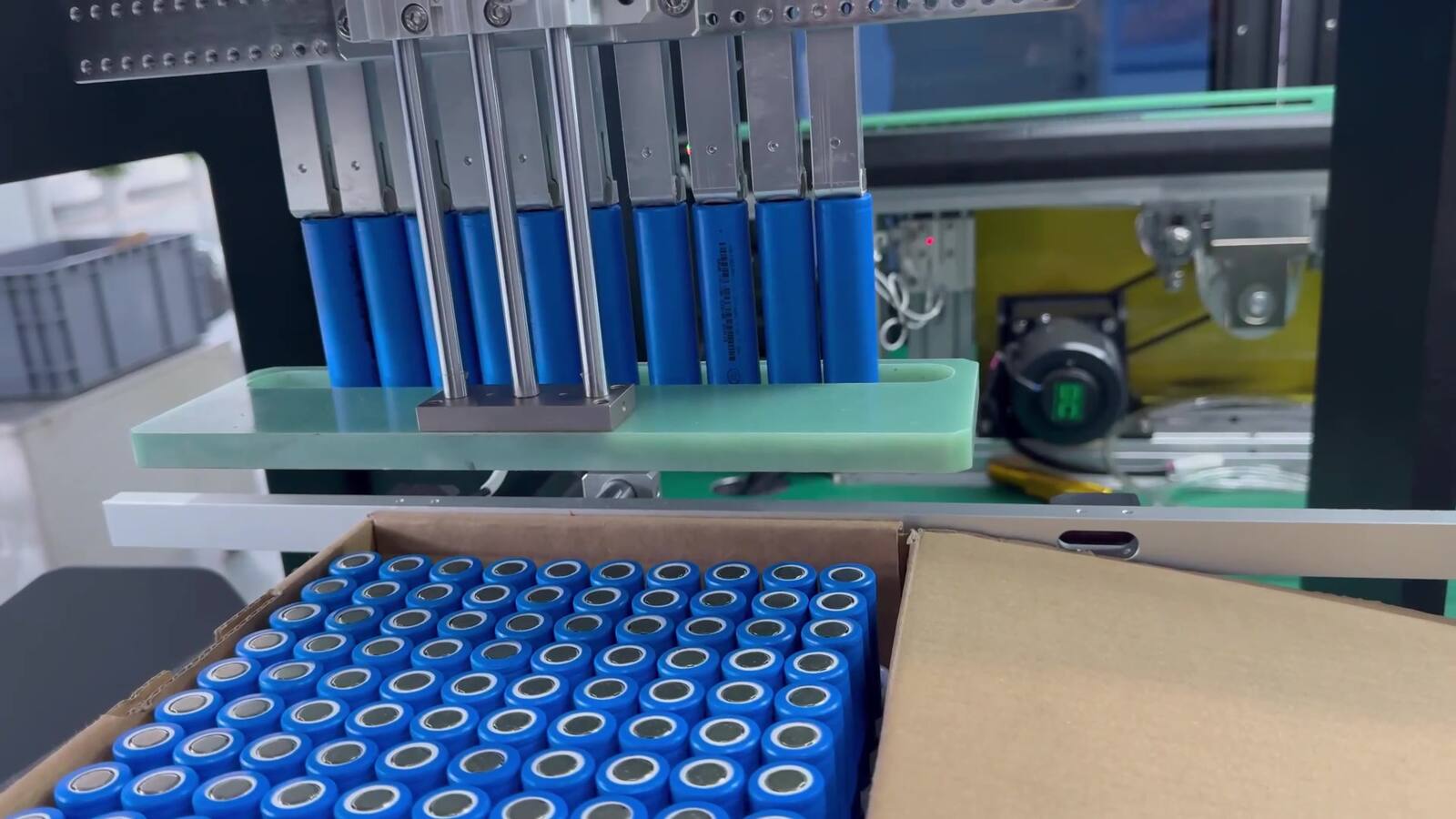 LBC cell-handling equipment lifting blue cylindrical cells from a loading tray