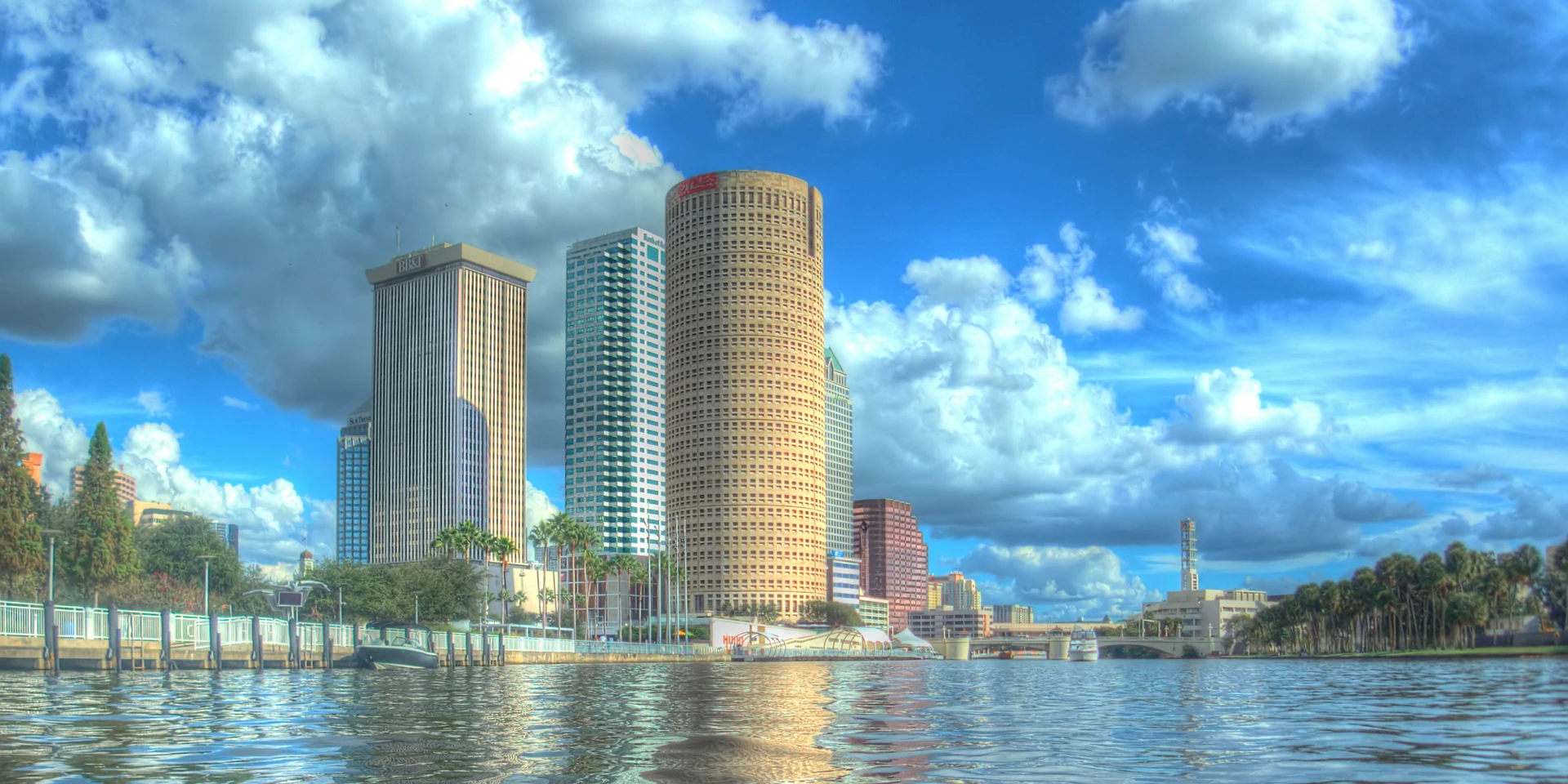 Downtown Tampa towers and waterfront reflected in the Hillsborough River beneath a blue sky
